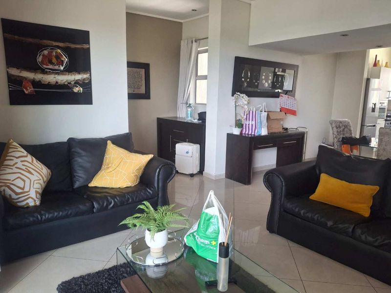 Spacious open-plan living area featuring neutral tiled flooring and recessed lighting, providing a versatile layout that flows seamlessly into the adjacent kitchen space.