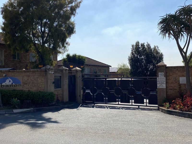Entrance view of the Lebanon residential complex featuring a secure gated access point with brick perimeter walls and electric fencing.