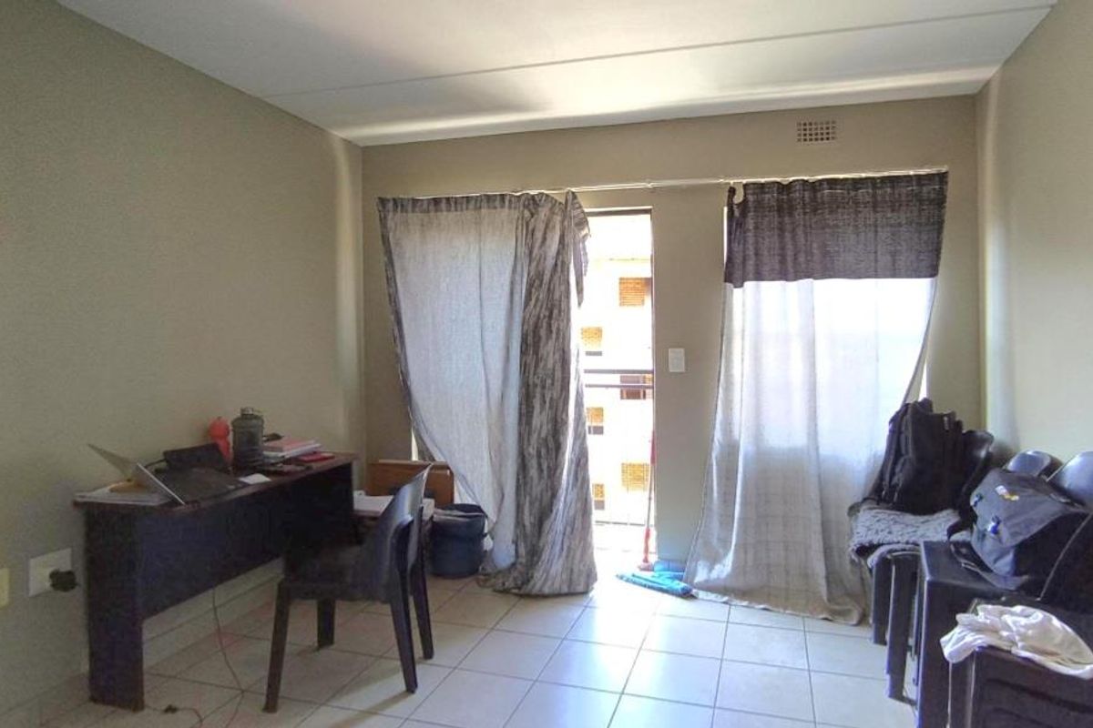 A functional living area featuring tiled flooring and a sliding door providing access to an outdoor balcony space.