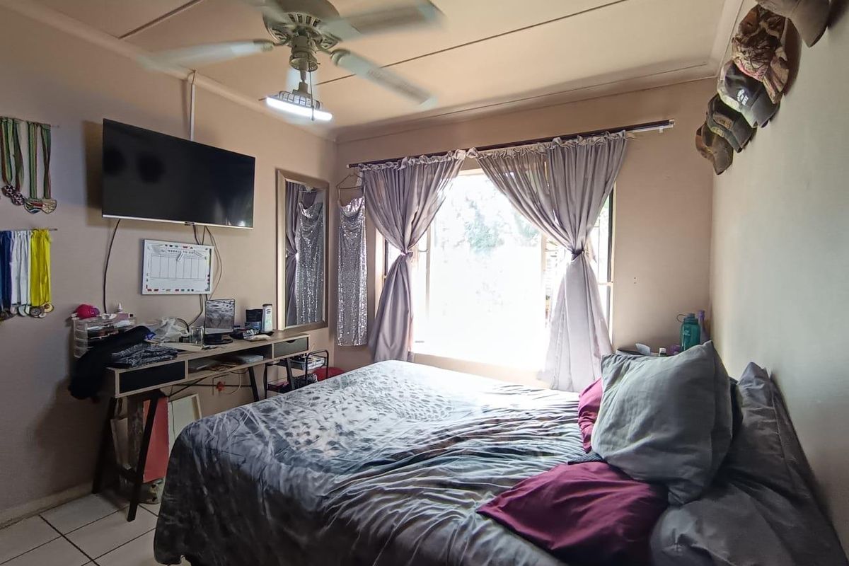 A functional bedroom featuring tiled flooring, a ceiling fan, and a window providing natural light.
