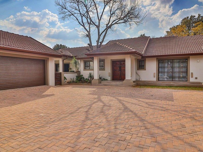 Front elevation of a residential house featuring a large paved driveway, double garage, and a covered entrance with tiled roofing.