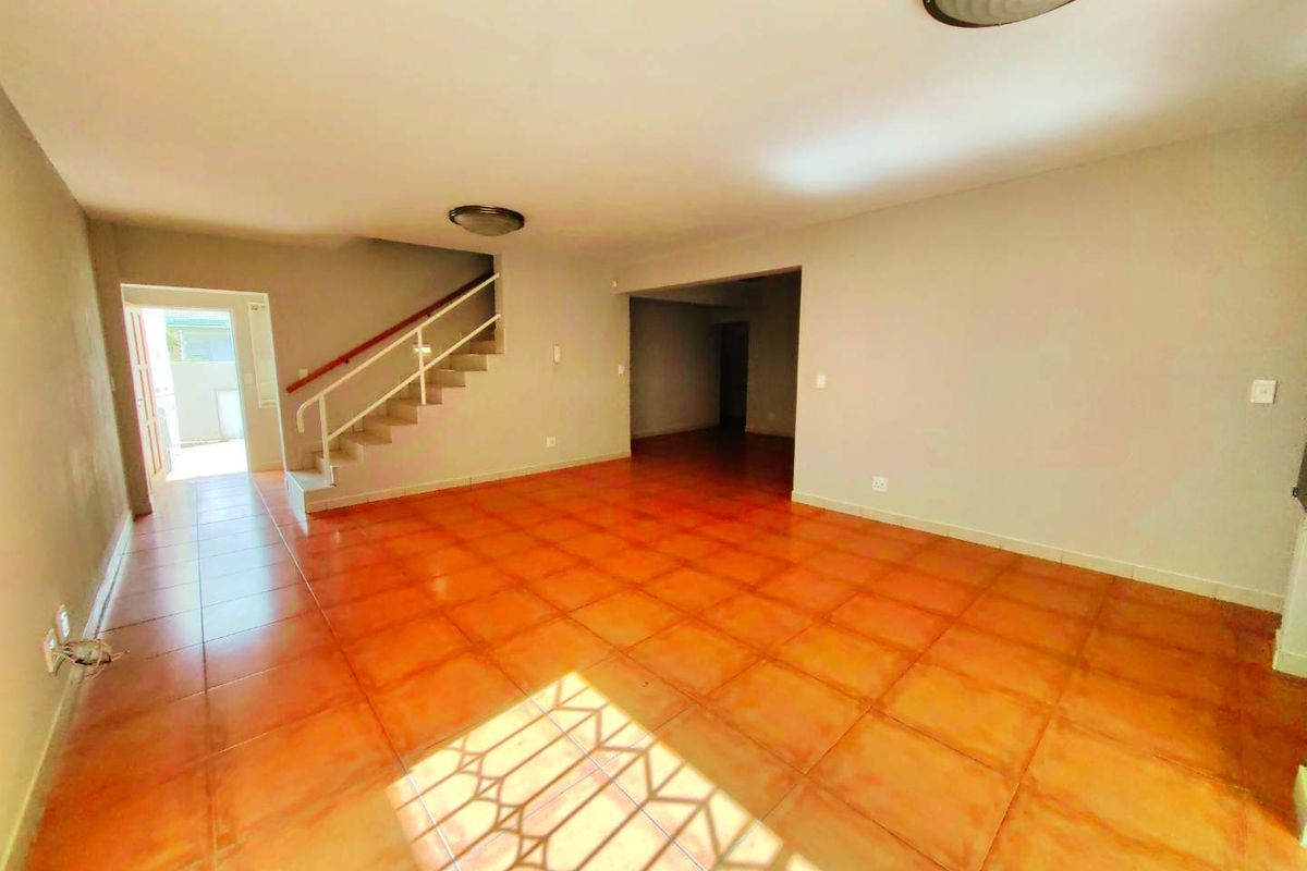 Spacious open-plan living area featuring tiled flooring and a staircase, presenting a blank canvas ready for interior design and modernization.