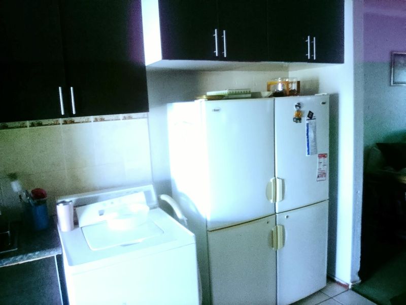 A functional laundry area featuring dark built-in cabinetry and tiled splashback, providing essential storage and utility space.