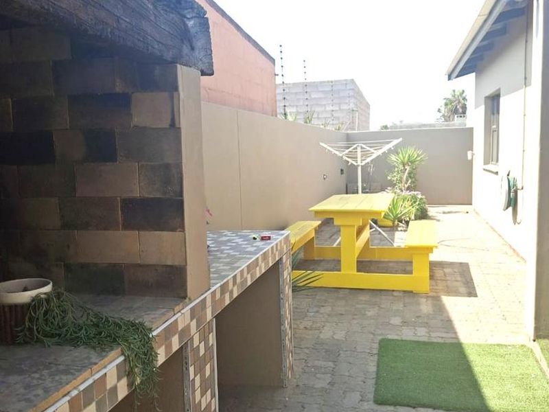 Outdoor patio area featuring a built-in brick braai with tiled prep surfaces and paved flooring, ideal for outdoor entertaining.