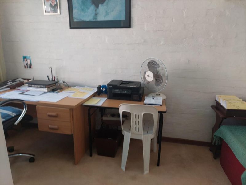 A functional home office space featuring a painted brick wall finish.