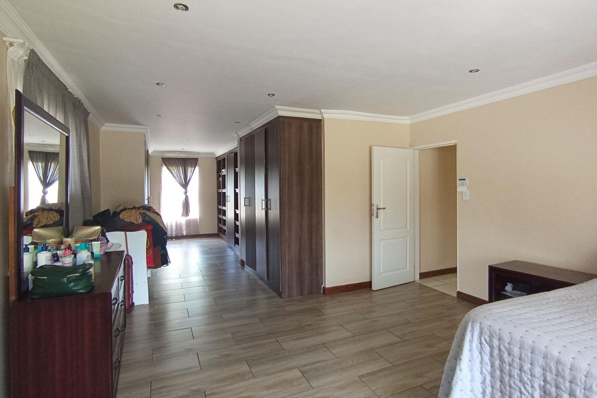 Spacious bedroom featuring built-in wooden cabinetry, tiled flooring, recessed ceiling lighting, and crown molding, offering a functional and well-maintained living space.