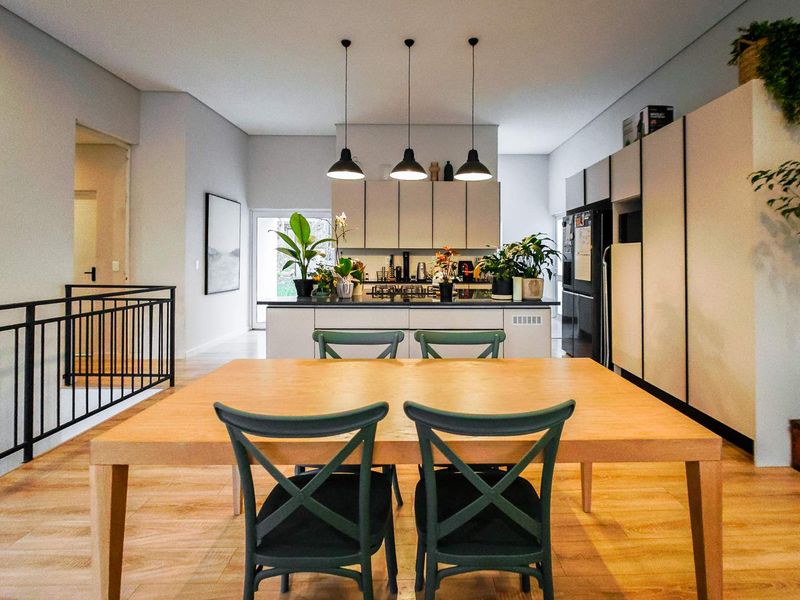 Modern open-plan kitchen and dining area featuring sleek cabinetry, a central island with pendant lighting, and light wood-look flooring.
