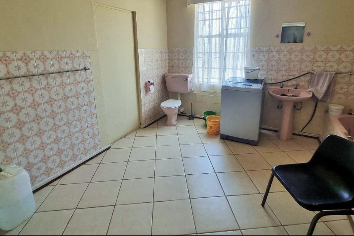 A functional bathroom featuring a pedestal basin, toilet, and bathtub with dated wall tiling and tiled flooring.