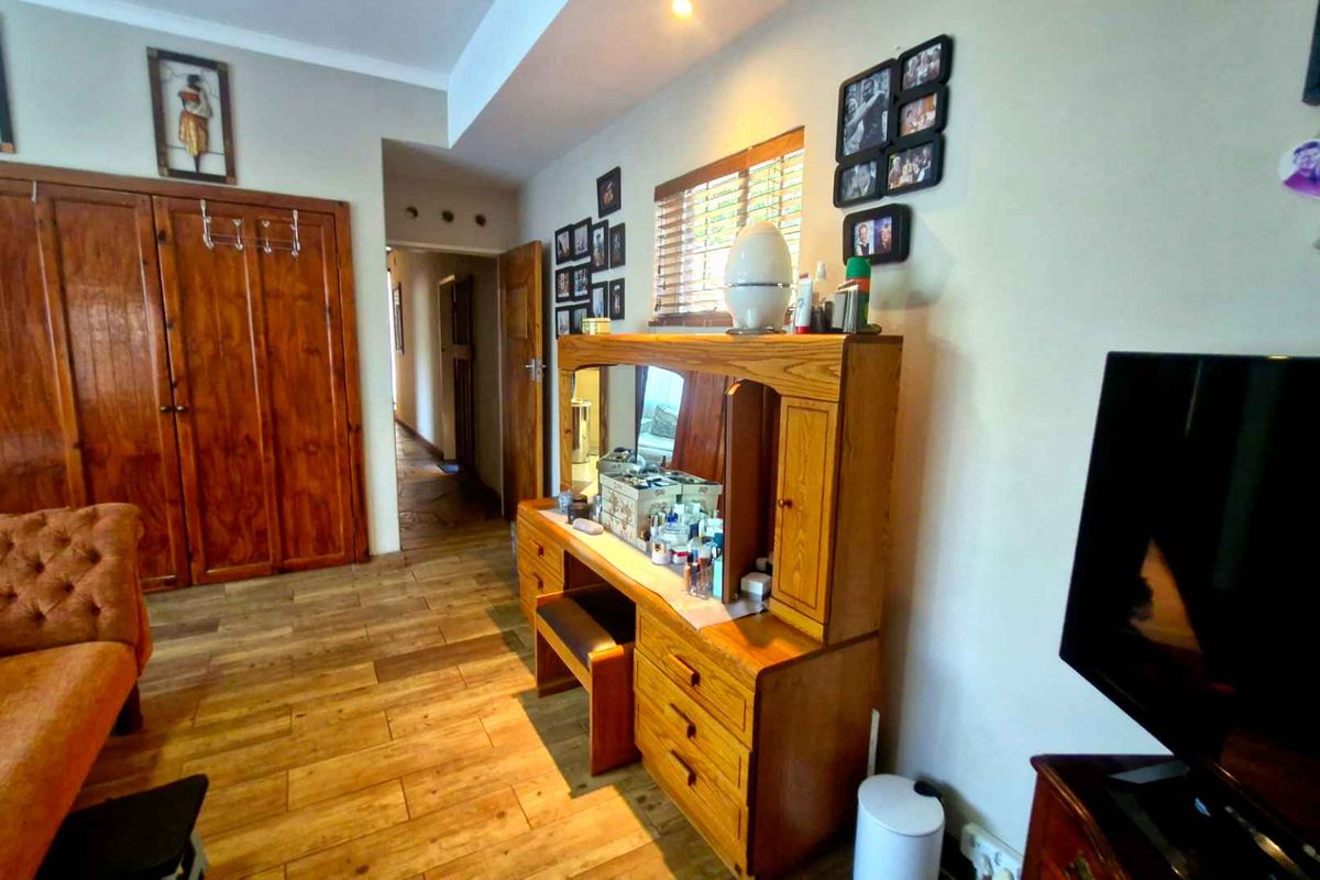 A bedroom featuring warm-toned wooden flooring and built-in wooden cabinetry, offering a traditional aesthetic with functional storage space.