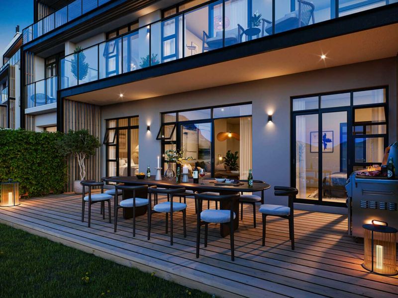 A modern ground-floor patio featuring timber decking, glass balustrades, and integrated exterior lighting, providing seamless indoor-outdoor flow to the apartment living space.