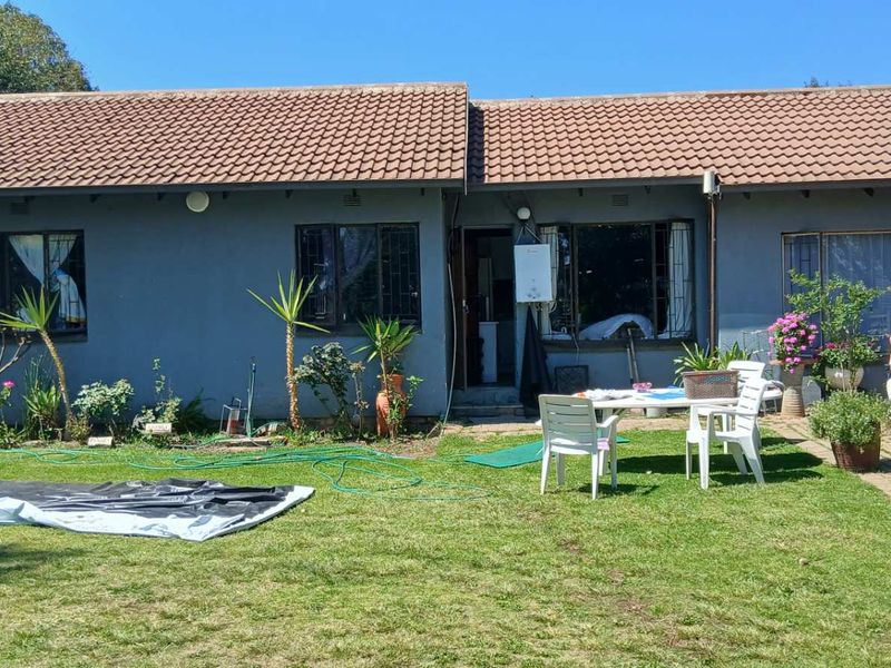 Rear view of a single-story house featuring a tiled roof, security bars on windows, and an external gas geyser unit.
