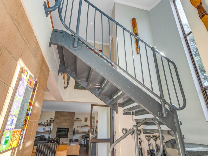 An entrance area featuring a striking metal staircase, double-volume ceilings, and exposed brickwork, creating an open and architectural feel.