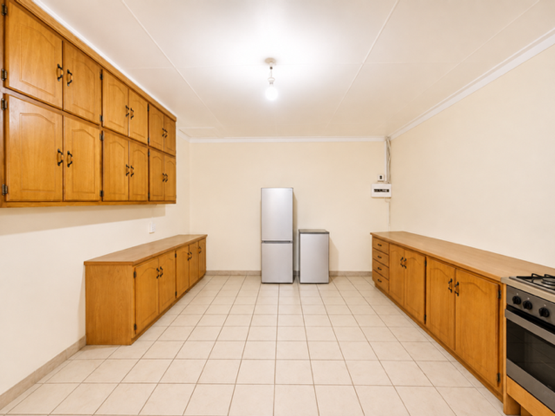 Spacious kitchen featuring extensive wooden cabinetry, tiled flooring, and a built-in oven and hob, offering ample storage and workspace.
