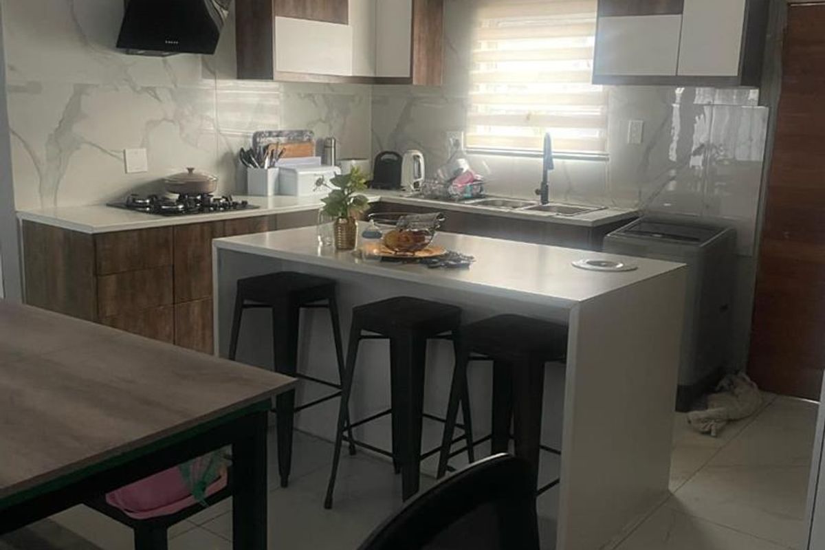 Modern kitchen featuring two-tone cabinetry, marble-look splashback, integrated gas hob with extractor fan, and a central island with breakfast bar seating.