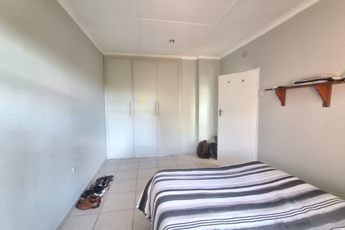 A bedroom featuring neutral wall tones, tiled flooring, and built-in wardrobe storage with a standard door entrance.