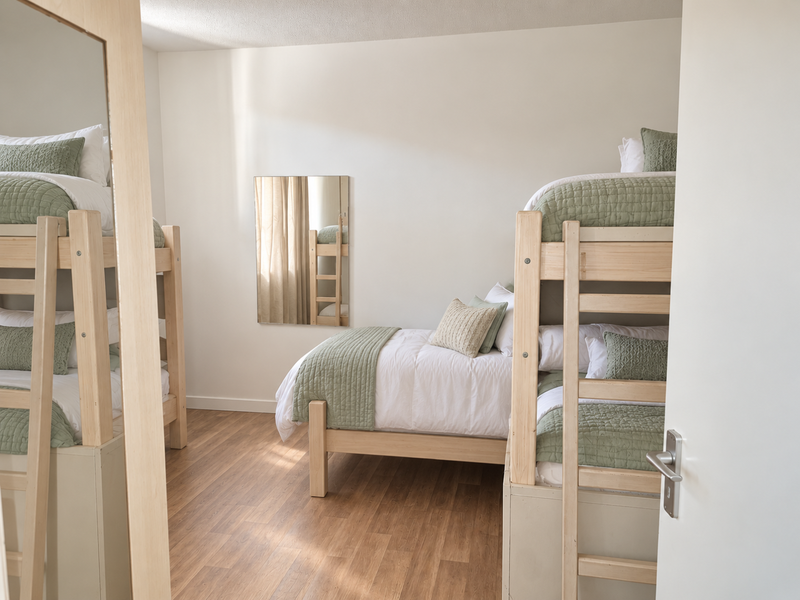 A well-maintained bedroom featuring light wood-look laminate flooring and neutral wall finishes, providing a clean and functional living space.
