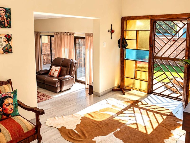 A bright living area featuring light-toned tiled flooring and a distinctive decorative stained glass security door leading to the exterior.