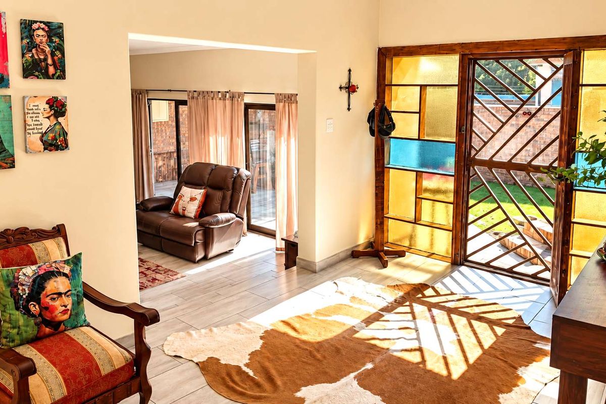 A bright living area featuring light-toned tiled flooring and a distinctive decorative stained glass security door leading to the exterior.