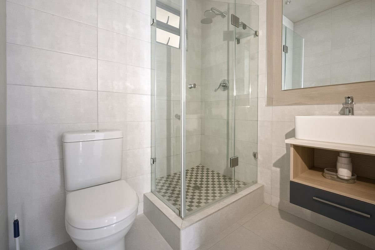 Modern bathroom featuring a glass-enclosed shower, wall-mounted vanity with vessel sink, and neutral tiled finishes throughout.