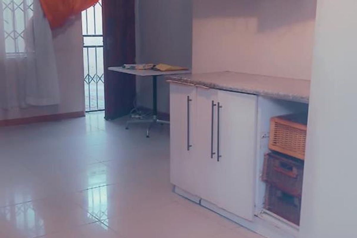 A functional kitchen area featuring white cabinetry, tiled flooring, and a built-in wine glass rack, providing a clean and practical workspace.