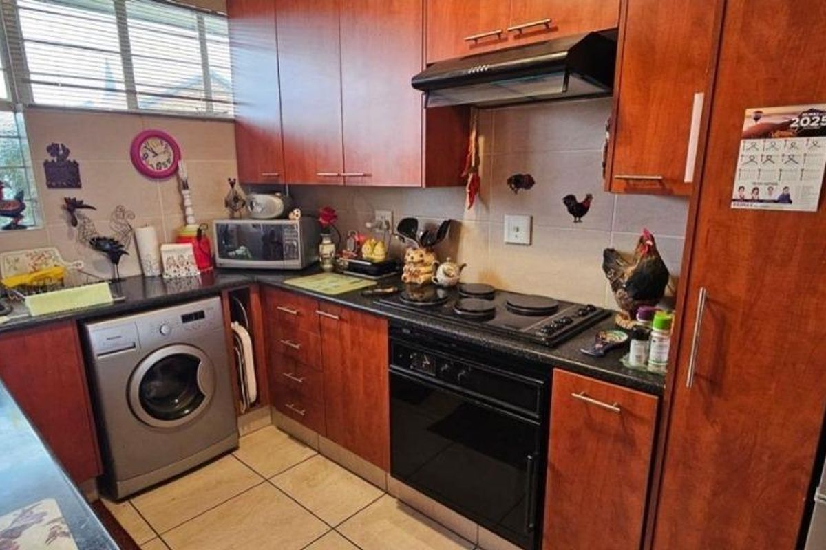 A functional kitchen featuring wood-finish cabinetry, dark countertops, a built-in oven with extractor fan, and integrated space for a washing machine.