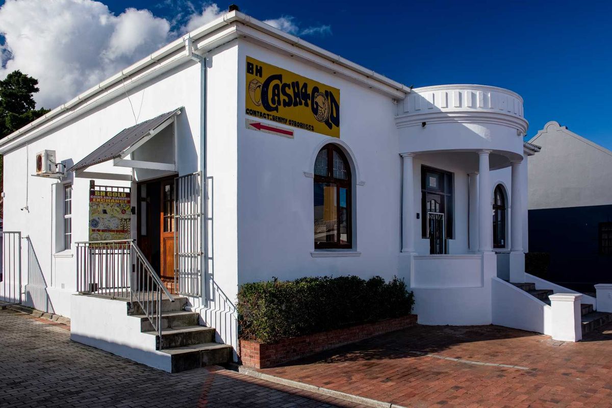 Front elevation of a commercial mixed-use building featuring a prominent portico, arched windows, and secure access points with brick-paved frontage.