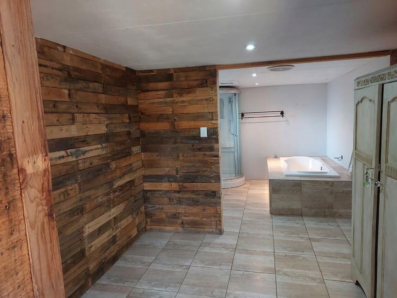 Bathroom featuring a built-in bathtub, separate shower enclosure, and rustic wood-paneled wall accents with tiled flooring.