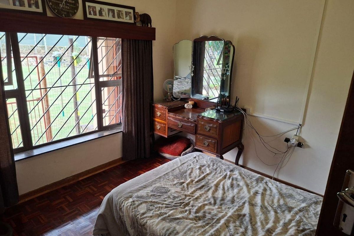 A bedroom featuring parquet flooring, a large window with security bars, and a built-in curtain pelmet.