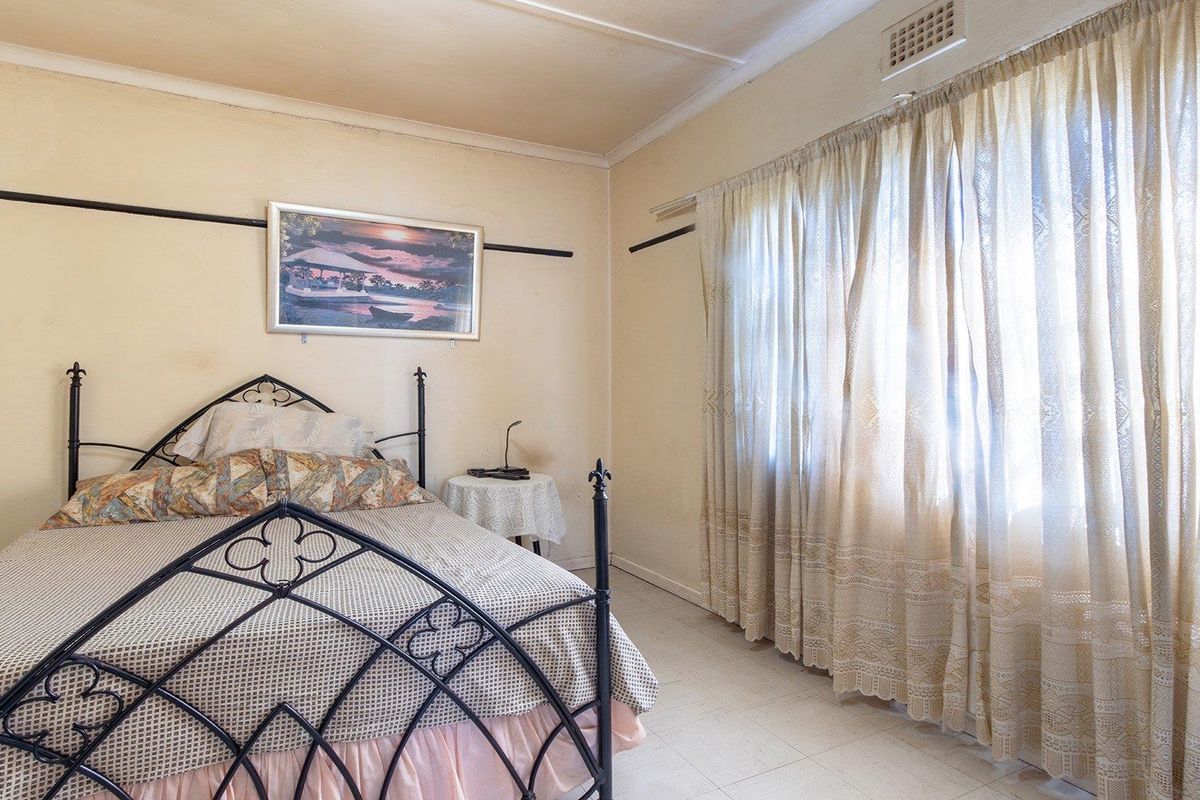 A bedroom featuring tiled flooring and a wall-mounted air vent, requiring cosmetic updates to the wall finishes.