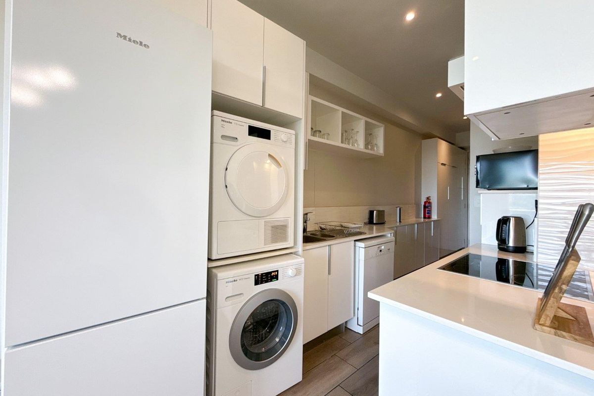 Modern kitchen featuring white cabinetry, integrated appliances, sleek countertops, and recessed lighting, offering a clean and functional culinary space.