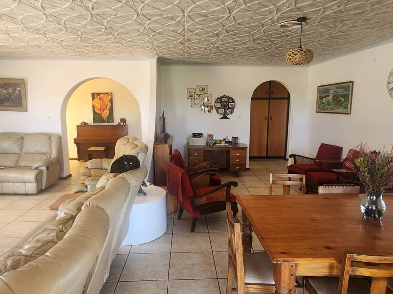 Spacious open-plan living and dining area featuring tiled flooring, distinctive decorative pressed metal ceilings, and classic arched architectural details.