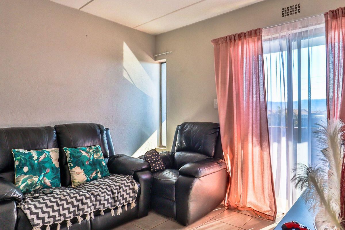 A living room area featuring tiled flooring and a sliding glass door providing access to an outdoor balcony space.