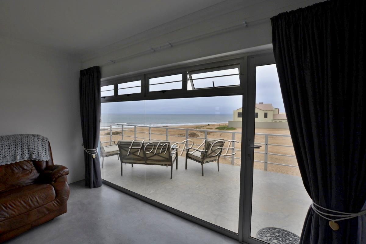 A bright living area featuring large sliding glass doors that open onto a balcony with direct ocean views.
