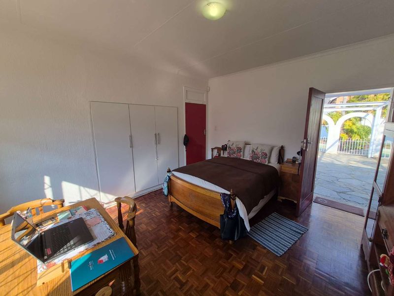 A bedroom featuring classic parquet flooring, built-in cupboards, and direct access to an outdoor patio area.