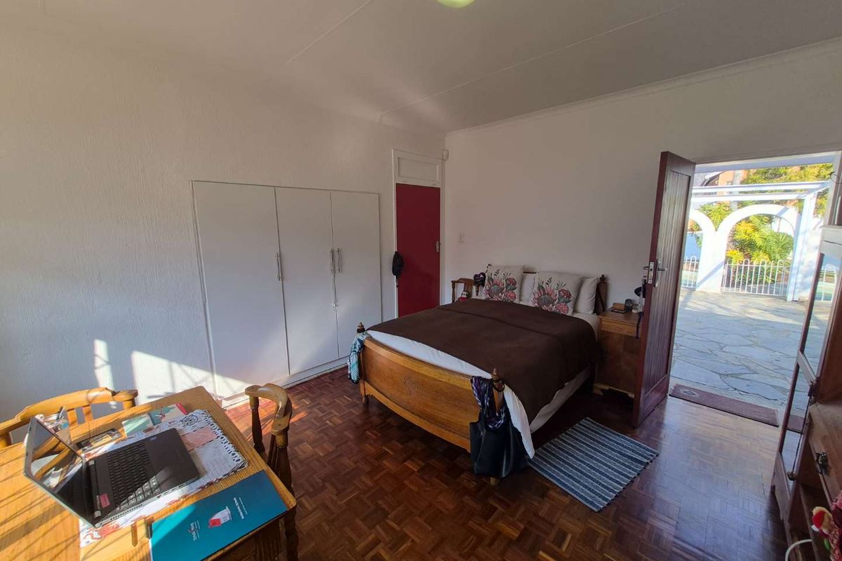 A bedroom featuring classic parquet flooring, built-in cupboards, and direct access to an outdoor patio area.