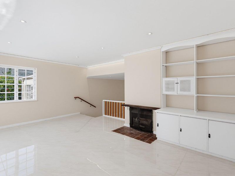 Spacious living area featuring polished tile flooring, built-in cabinetry, a fireplace with a tiled hearth, and recessed lighting.