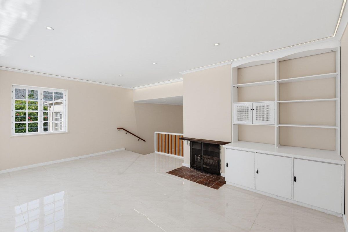 Spacious living area featuring polished tile flooring, built-in cabinetry, a fireplace with a tiled hearth, and recessed lighting.