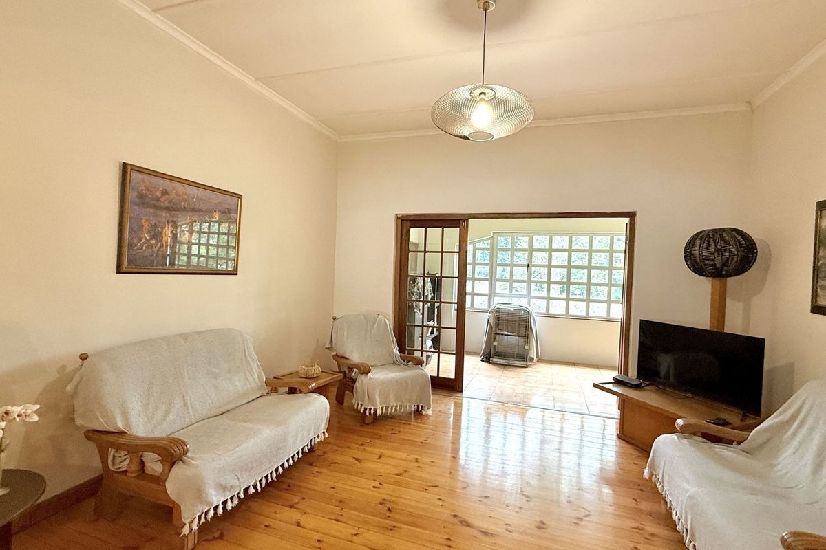 A living room featuring polished timber flooring and a glass-paned door leading to an enclosed patio area.