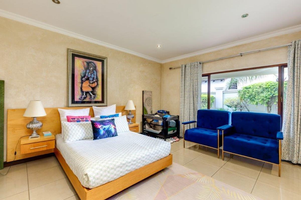 Spacious bedroom featuring tiled flooring, recessed downlights, and a large sliding glass door providing natural light and garden access.