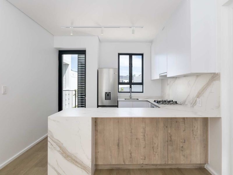 Modern kitchen featuring marble-look stone countertops, wood-grain cabinetry, gas hob, and integrated stainless steel sink with clean, contemporary finishes.