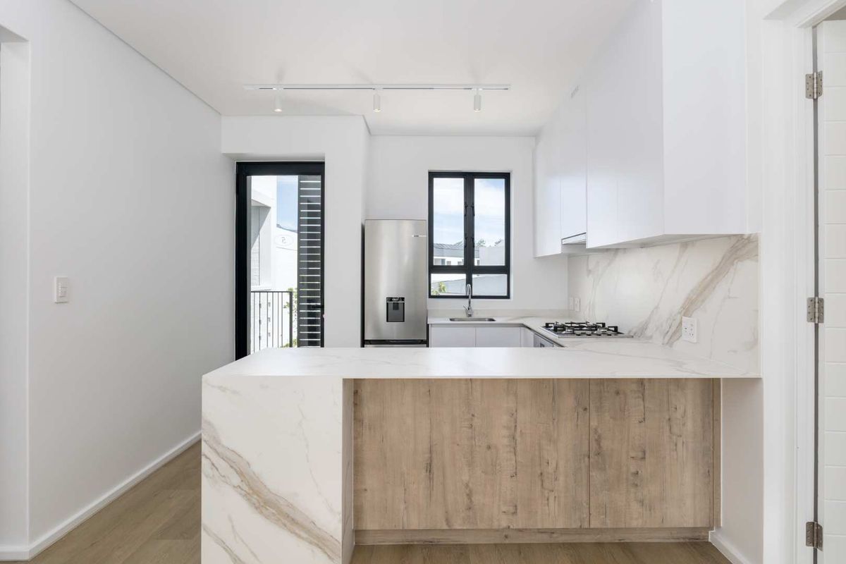 Modern kitchen featuring marble-look stone countertops, wood-grain cabinetry, gas hob, and integrated stainless steel sink with clean, contemporary finishes.