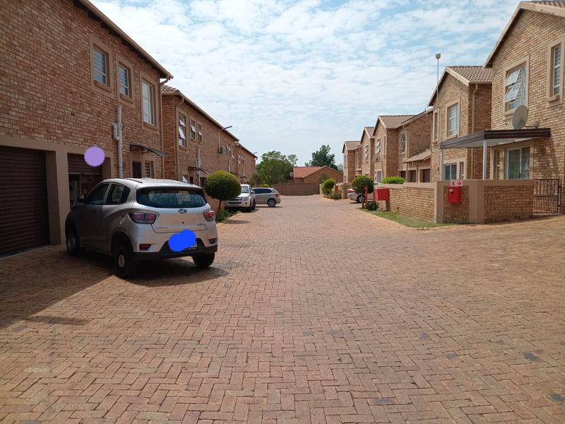 A view of the complex driveway featuring face brick apartment buildings with paved access and integrated garage doors.
