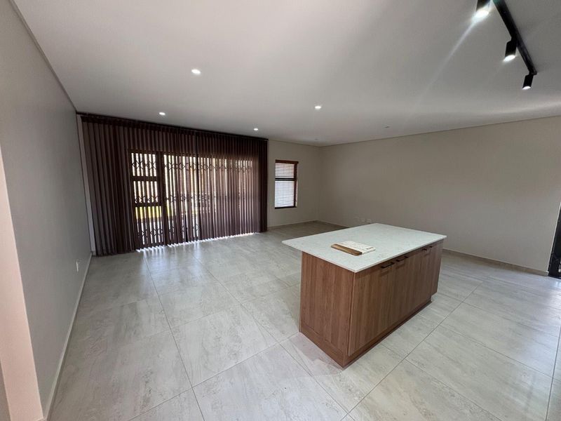 Spacious open-plan living area featuring modern tiled flooring, recessed lighting, and a central kitchen island with a stone countertop.