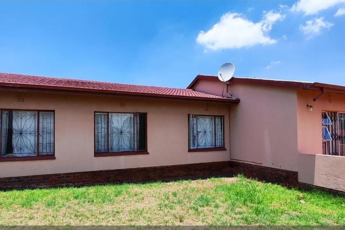 Rear exterior view of the house featuring a tiled roof, brick base, and security bars on the windows.