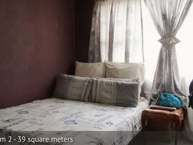 A compact bedroom featuring dark painted walls and a window with curtains, providing a functional sleeping space.