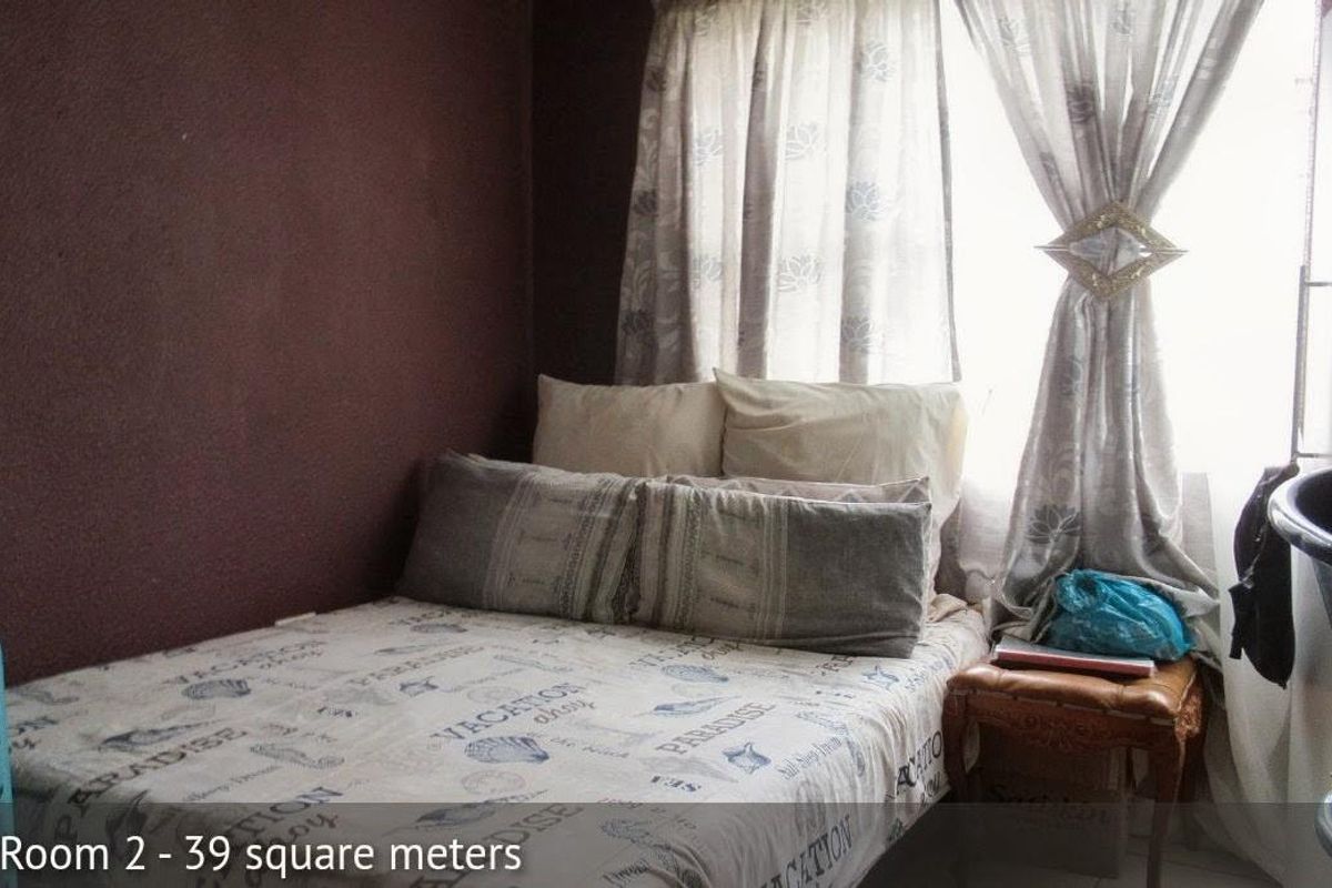 A compact bedroom featuring dark painted walls and a window with curtains, providing a functional sleeping space.