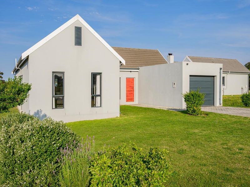 A modern single-story residential home featuring a clean facade, tiled roof, paved driveway, and an integrated garage.