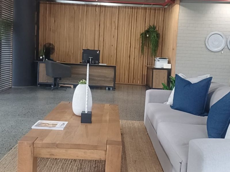 Modern open-plan retail or office space featuring polished concrete floors, timber slat wall accents, and exposed industrial-style fire sprinkler piping.