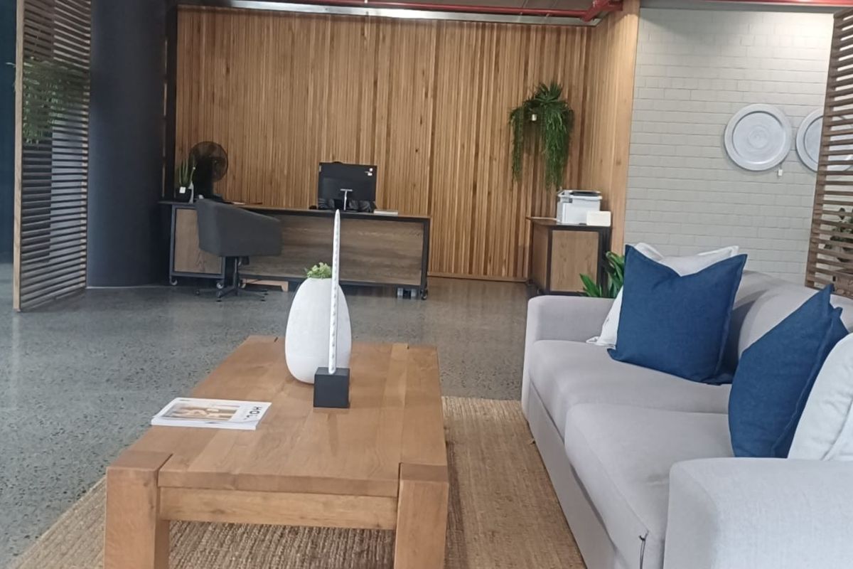 Modern open-plan retail or office space featuring polished concrete floors, timber slat wall accents, and exposed industrial-style fire sprinkler piping.