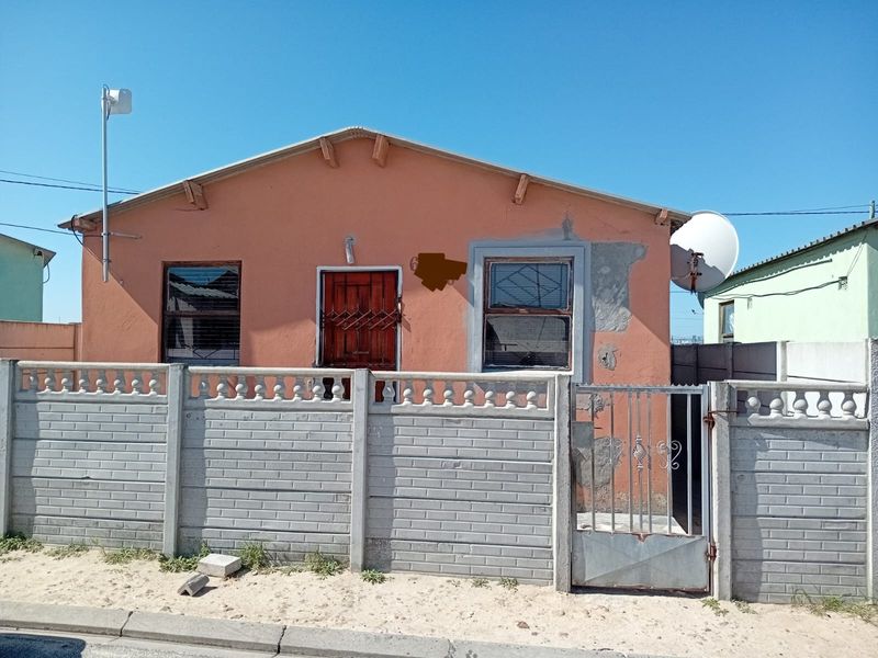 Front elevation of a single-story house featuring a precast concrete boundary wall, metal security gate, and exterior wall requiring maintenance and repainting.